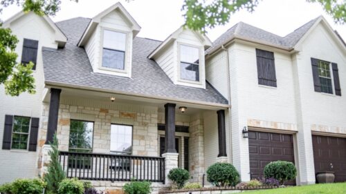 Exterior of a large stone house with white stucco painted by professional painters in Moore