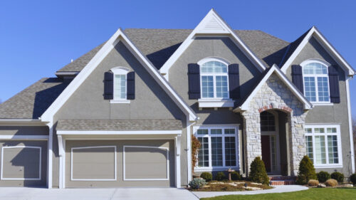 Large stone accented house with gray stucco painted by house painters in Norman