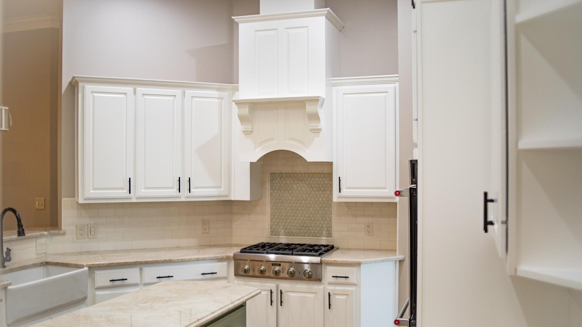 Pearland Texas home kitchen with cabinets above the stove painted white.
