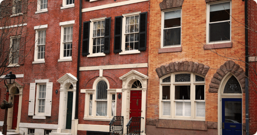 Exterior painting in Philadelphia of historic Federal-style rowhomes with red and tan brick facades, arched windows, and decorative lintels and shutters by that 1 painter.