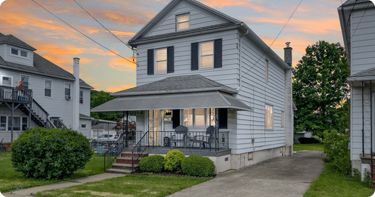 Exterior painting in Scranton of a traditional two-story home with light blue siding, dark shutters, and a front porch under a sloped roof with wrought-iron railings by that 1 painter.