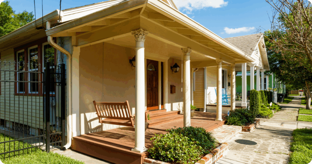Exterior painting in Shreveport of a charming bungalow with stucco and clapboard siding, a wood porch swing, and decorative column details by that 1 painter.