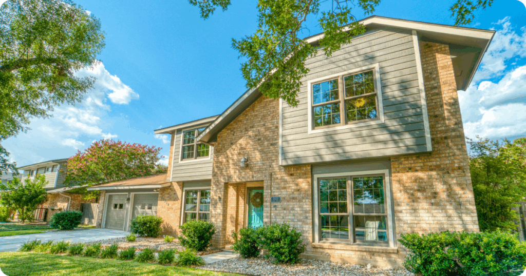 Exterior painting in Treasure Valley showcasing a two-story home with light brick and gray siding, teal front door, and neatly landscaped front yard by that 1 painter