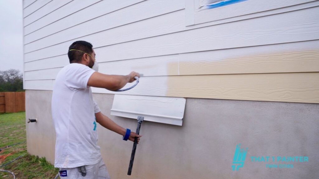 A professional painter in the Twin Cities using a sprayer to spray the exterior of a home