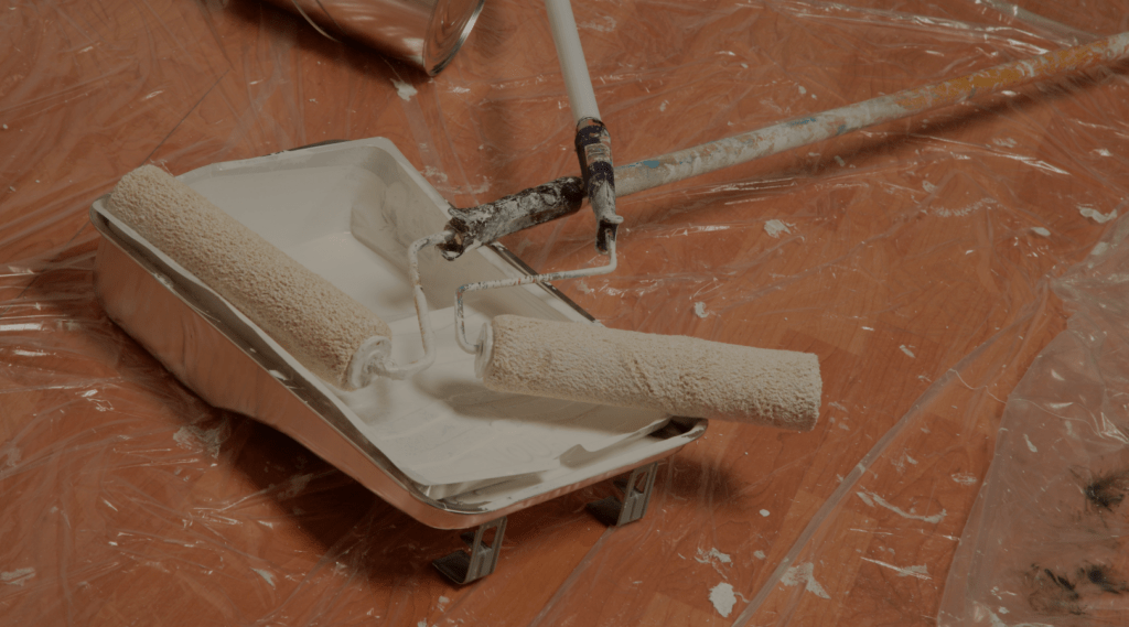 paint roller with paint cover on ground and white paint for that 1 painter