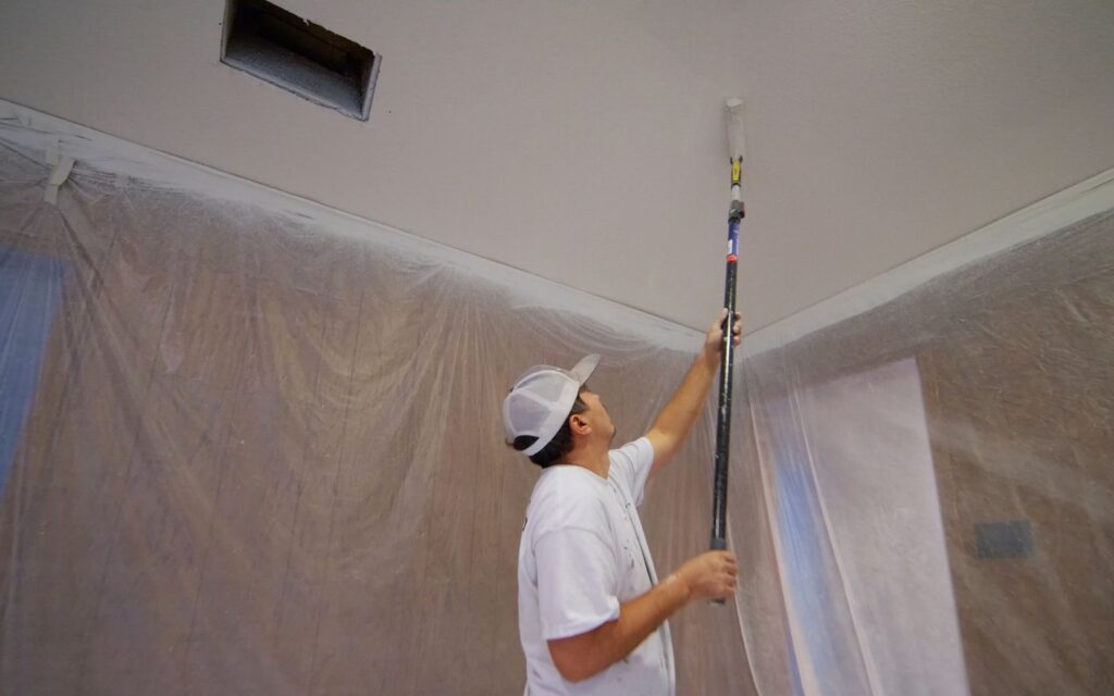 What Paint Finish Should I Use? Guide to Better Results 1 Professional painter using a roller with an extension to apply flat paint finish to a ceiling