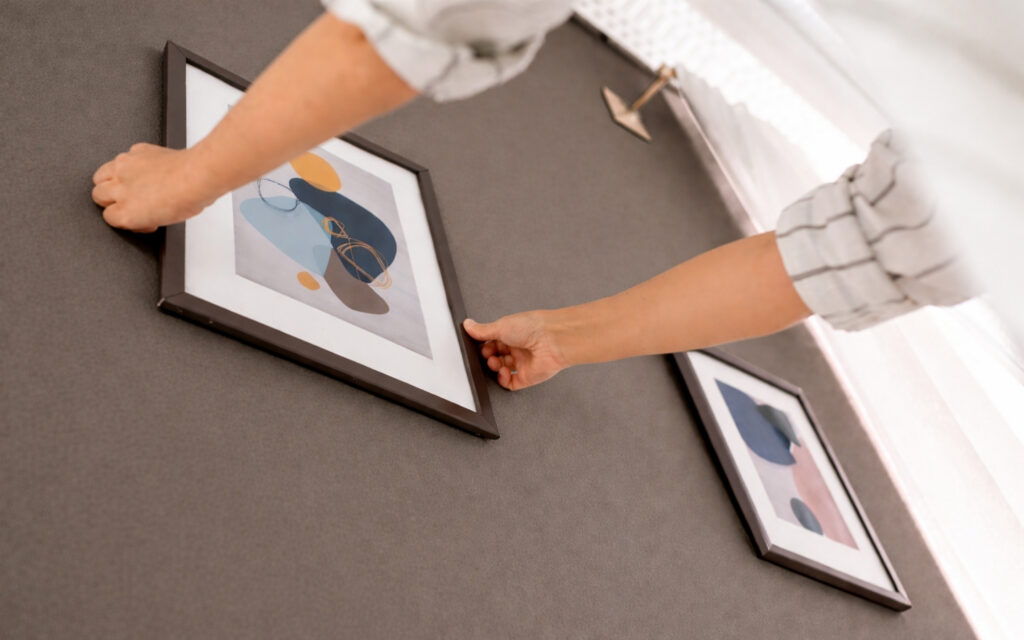 What Is Paint Color Drenching? The Divisive Viral Paint Trend 2 two hands hanging a small picture on the wall in a color drenched painted room